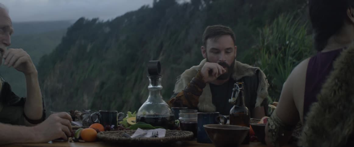 People dine at an outdoor table while wearing medieval clothing