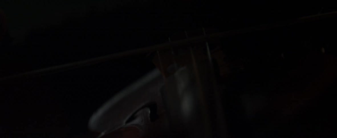 A person plays violin in a dark environment