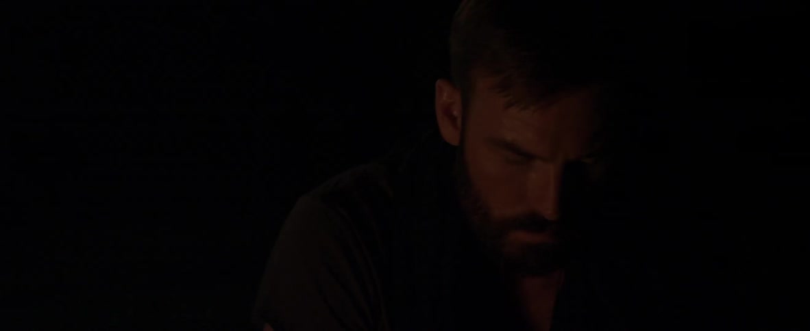 A man is looking down next to a campfire