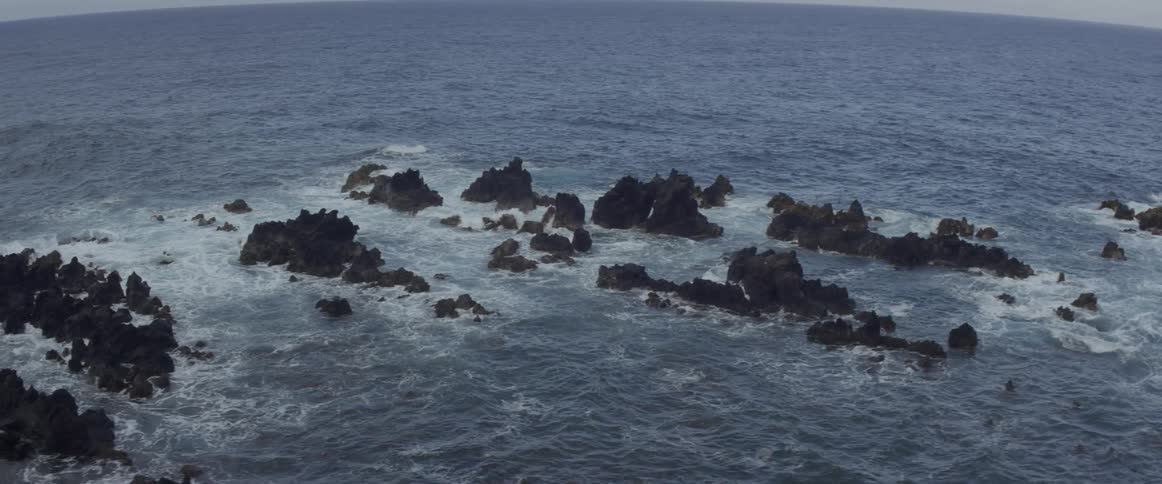 Waves crash and churn around rocks in the ocean
