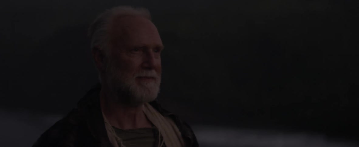 An old man is smiling and staring