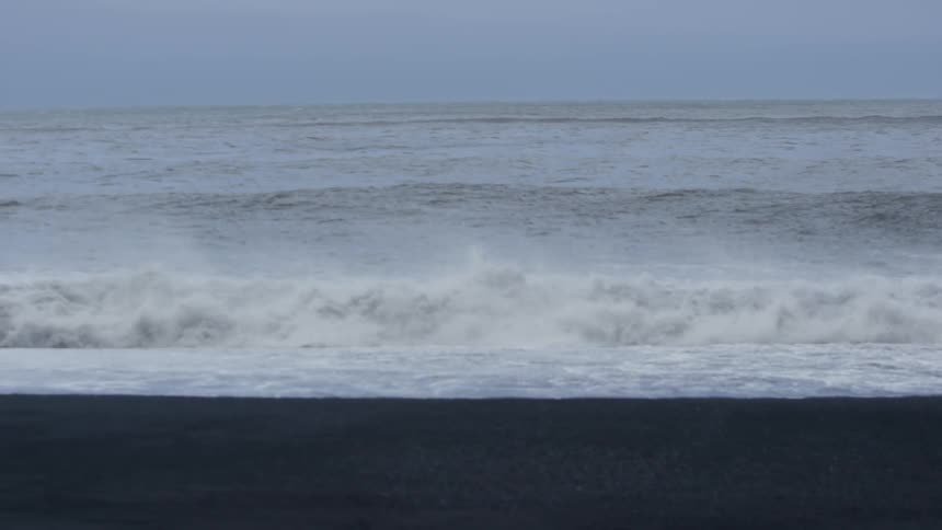 Waves crash on the beach on an overcast day