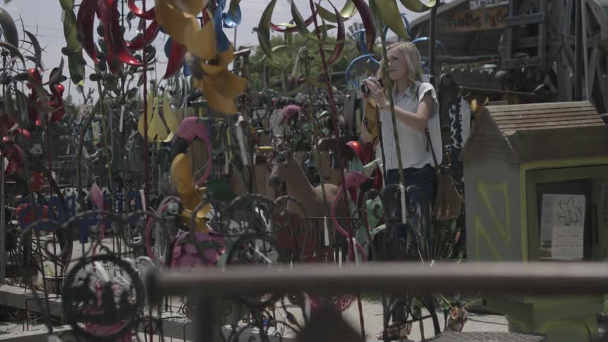 A woman browses garden decorations and takes a picture