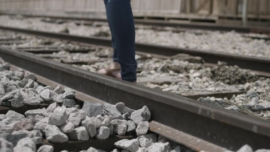 A woman walking along railroad tracks