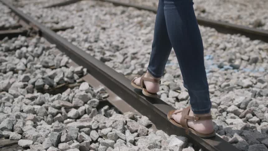 A woman walks along a railroad track