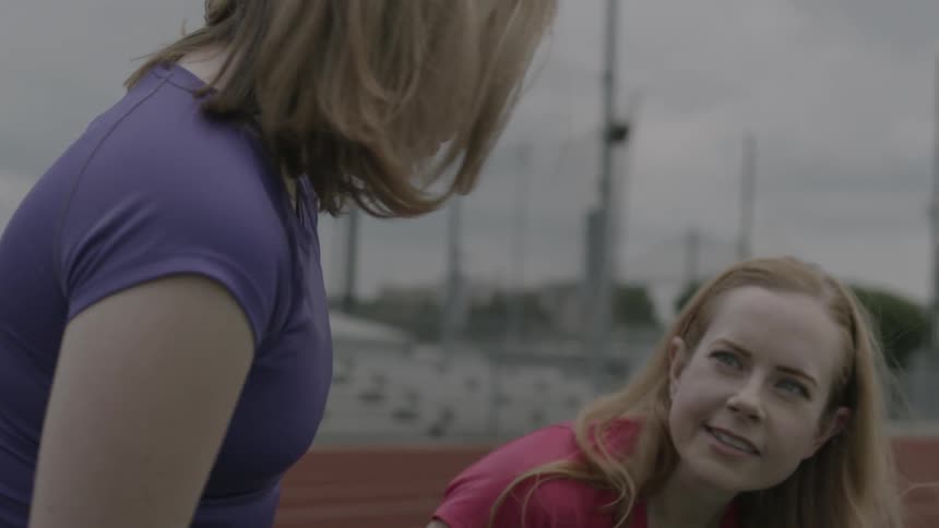 Women sit on a bench next to a running track