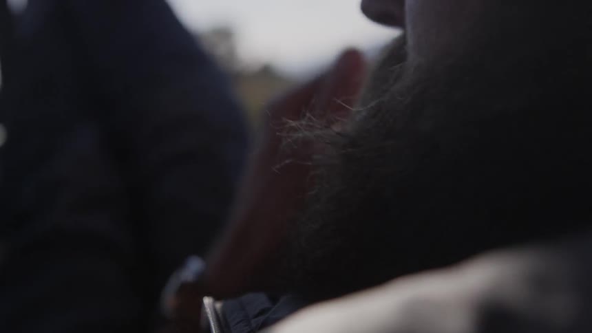 A man with a beard rides in a car in the daytime