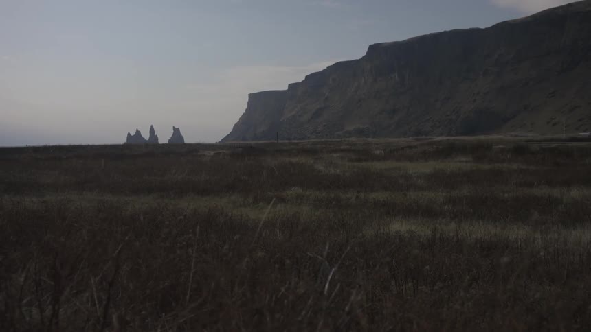 An empty field next to a rocky cliff