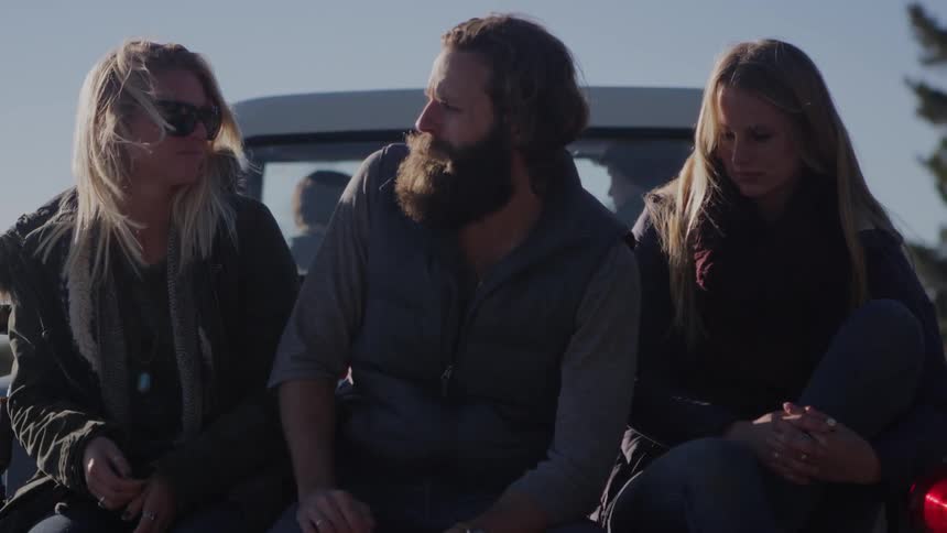 Man and two women sitting in the back of a truck
