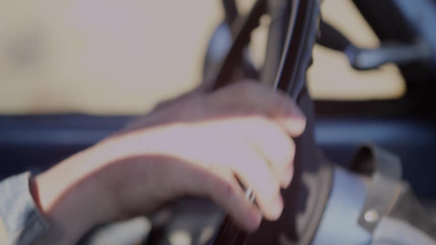 A person sitting in the driver's seat is turning the steering wheel