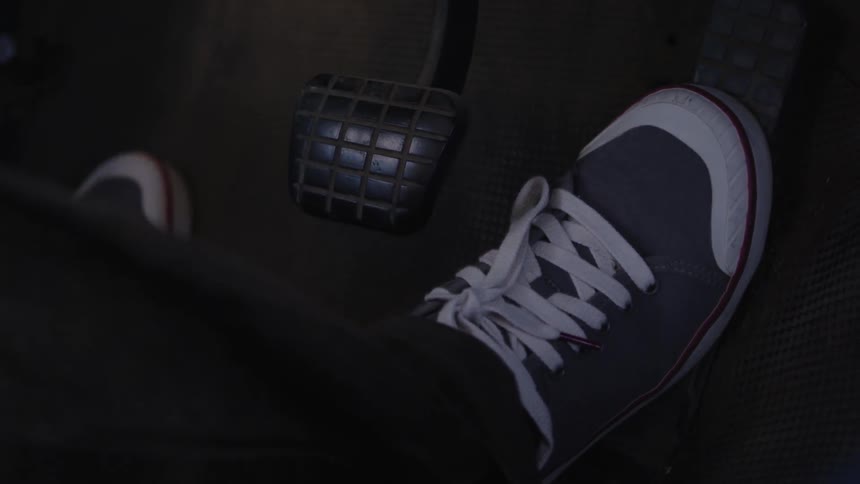 A shoed foot presses on a gas pedal