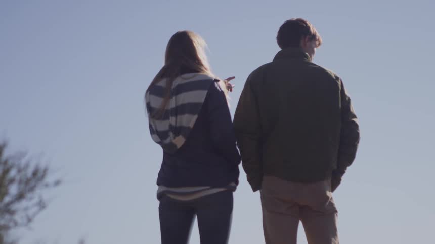 A couple is standing outdoors on a sunny day
