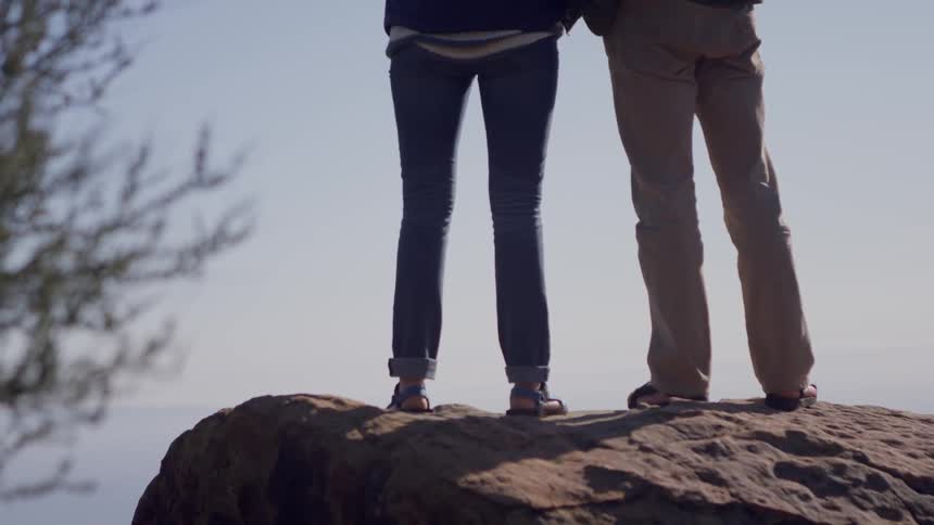 Two persons stand on the edge of the rock