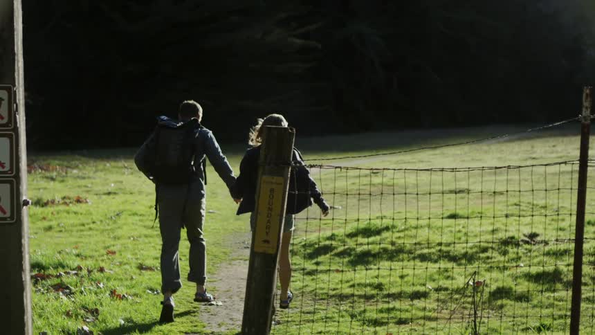 A couple run past the gate onto the field
