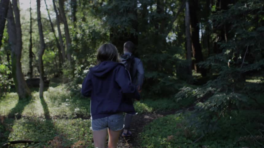 A man and woman run through the forest