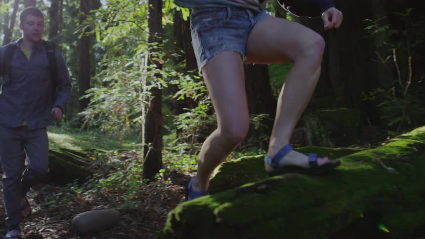 A man and woman run through the forest
