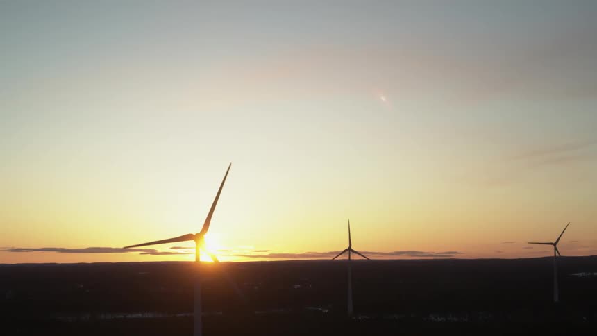 The sun sets behind the windmills