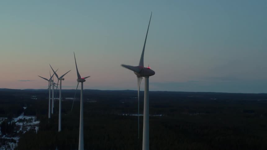 Spinning windmills in a row at susnset