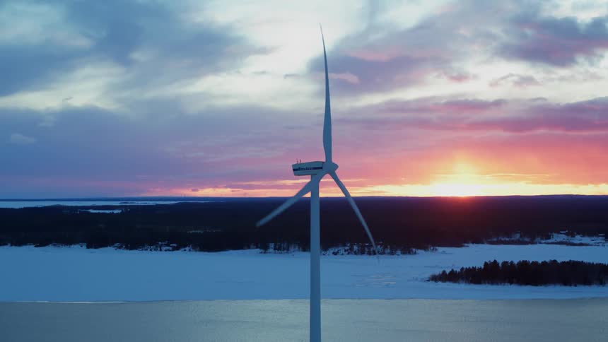 A windmill blade rotates as the sun sets