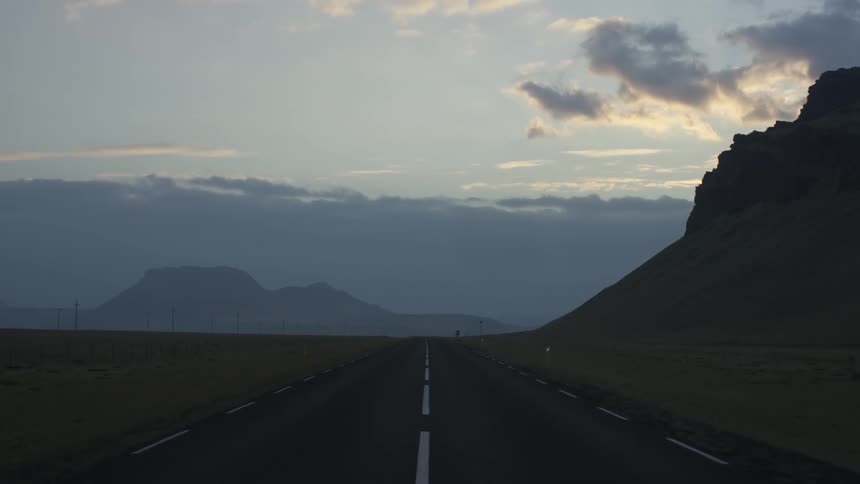 A long and straight highway through open plains and mountains