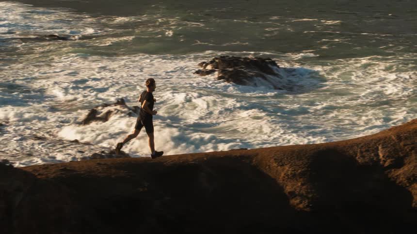 A man jogs along a coastal ridge-line during the day