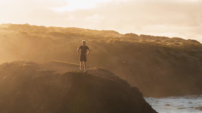 A man has climbed on the cliff by the water