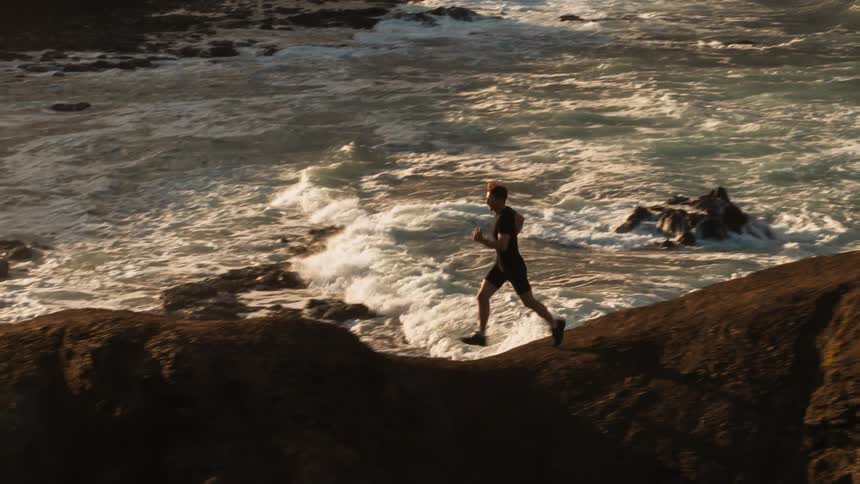 The man jogs down the hill towards the water