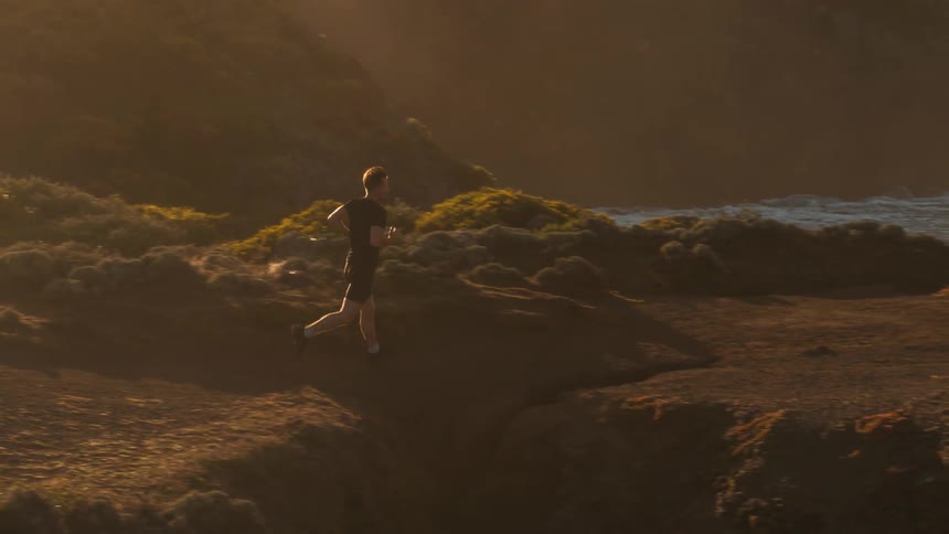 A man jogs along a hilltop on the coast