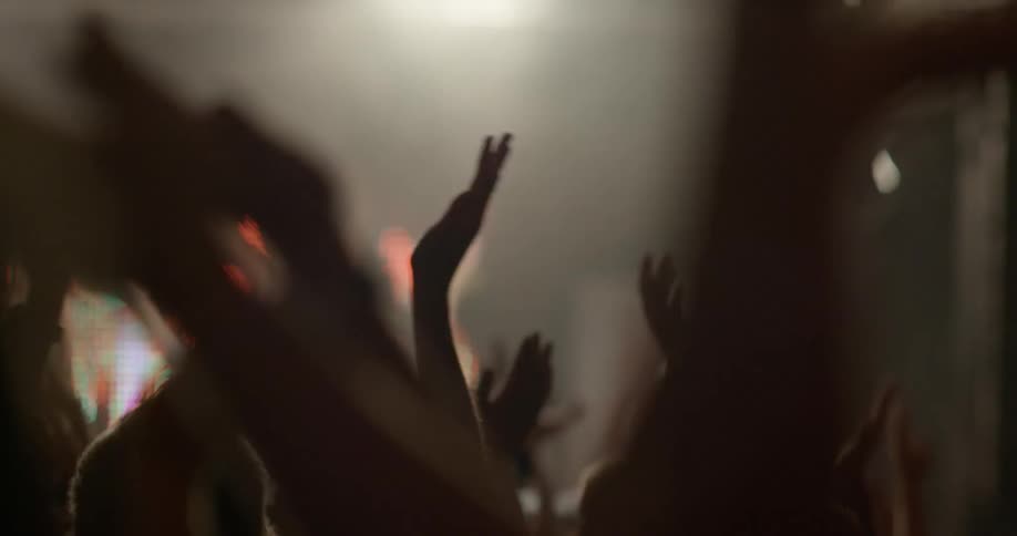 Crowd of people with hands in the air clapping at concert