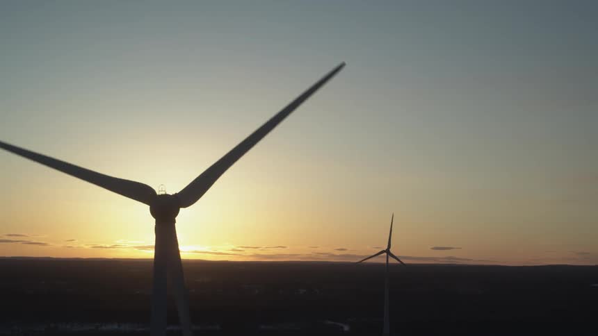 Windmills turn as the sun sets
