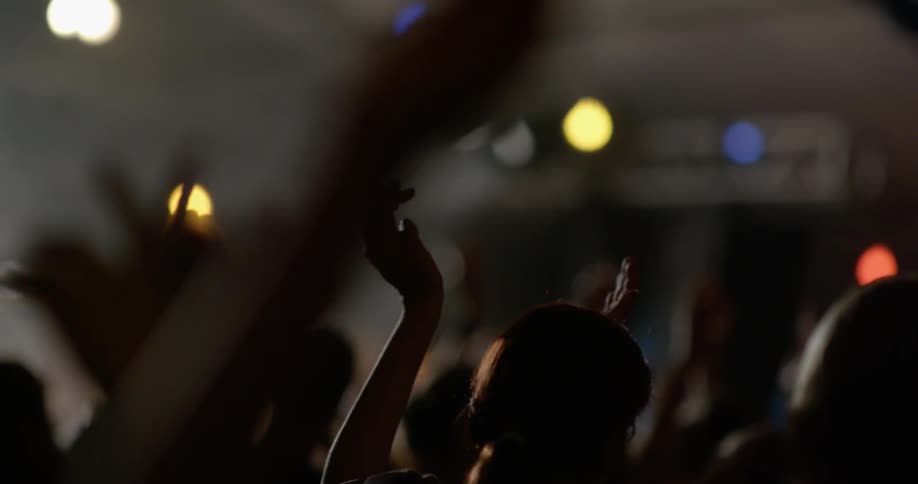 People clapping their hands in a lighted room
