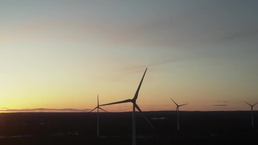 Wind turbines rotate at sunset