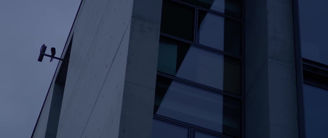Glass windows are being filmed from the sidewalk