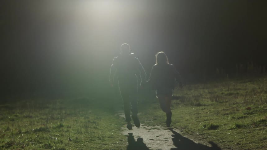 Couple runs along the narrow path towards the darkness