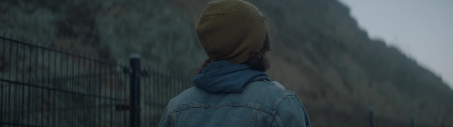 A man is walking near a fence