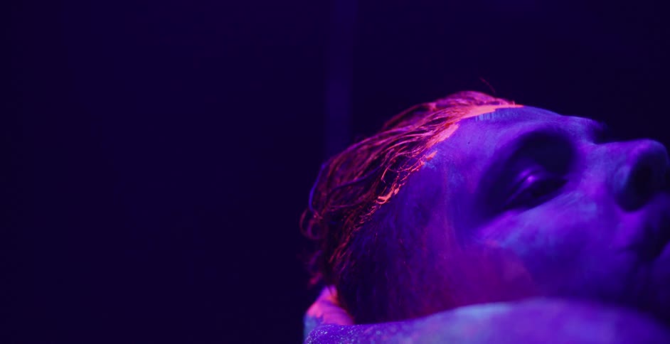A man wipes his hair back leaving glowing paint