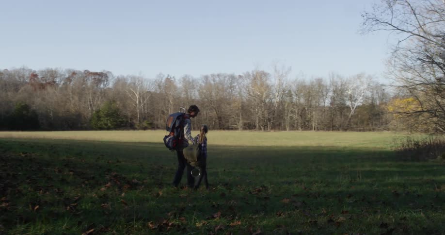 A man and child hike over the field