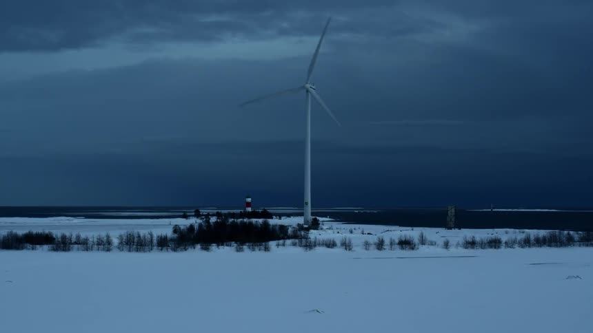 Single windmill spinning in the middle of a snowy field