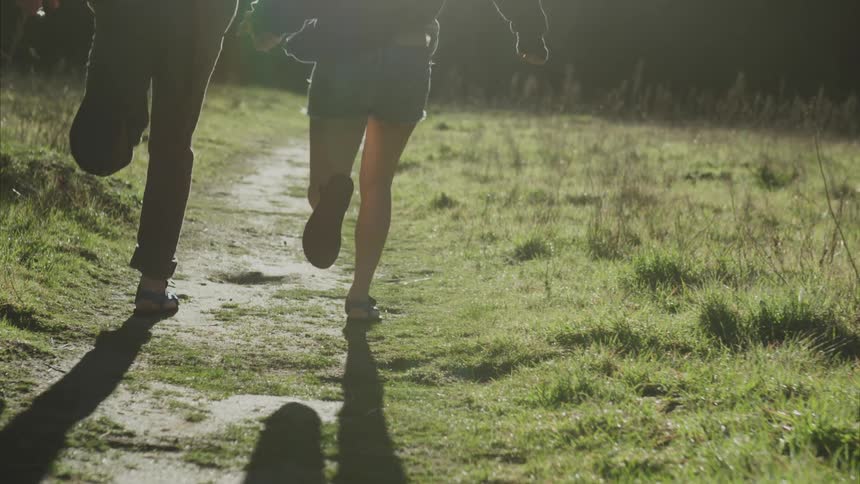 A couple is jogging on a dirt path