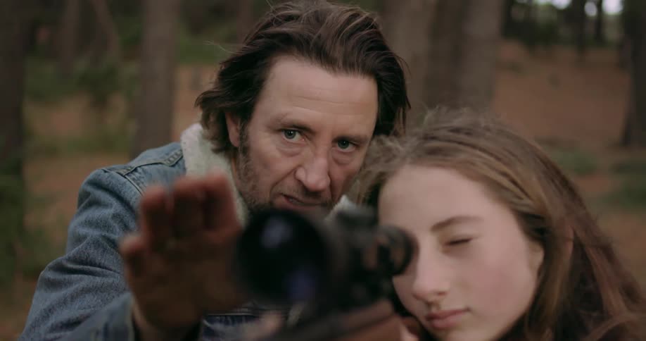 Man teaches a teenage girl how to shoot a gun