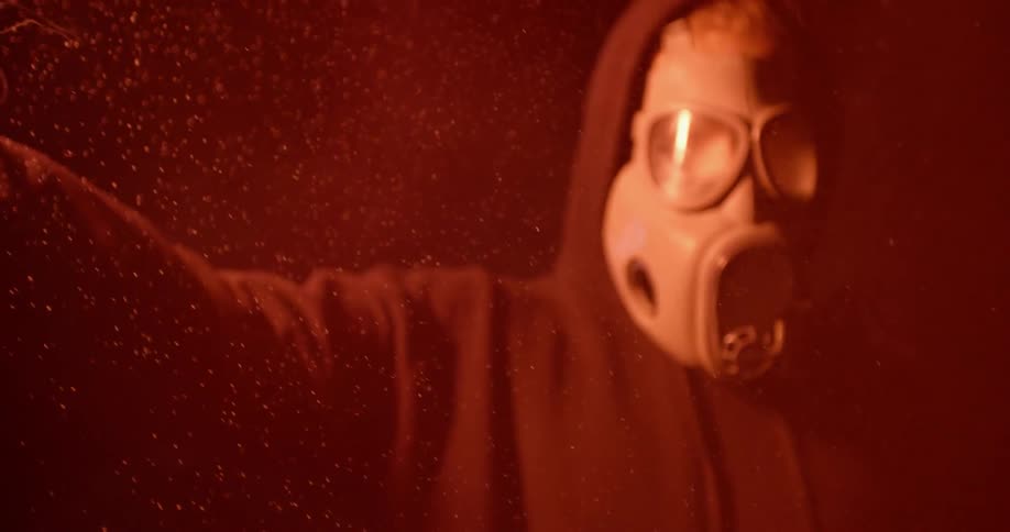 A man wearing a gas mask holds a lit flare