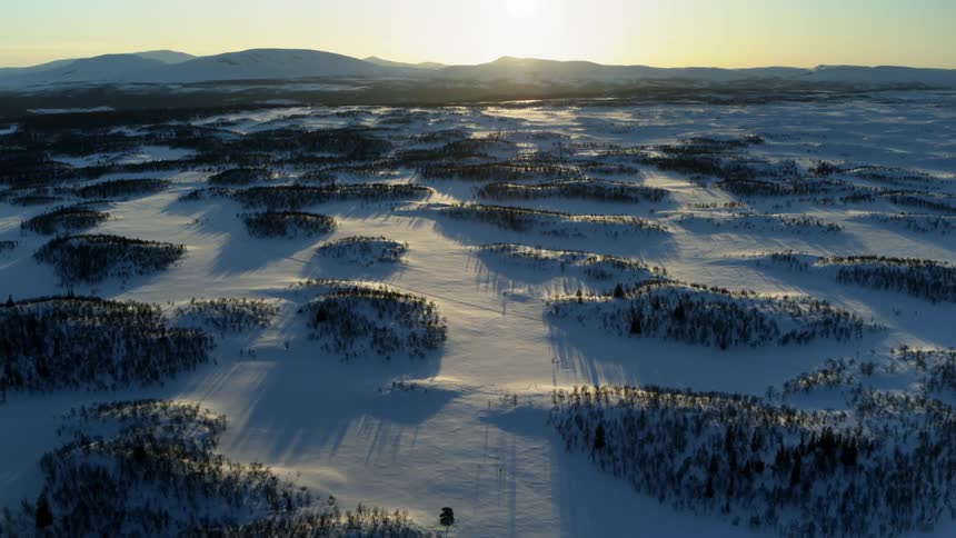 The sun sets over snowy mountains
