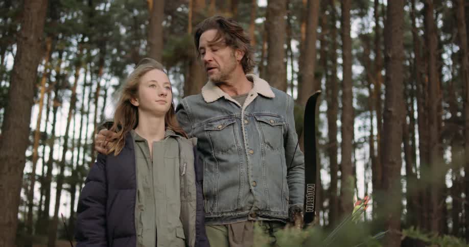 Man has his arm around his daughter as he holds a bow with his other hand