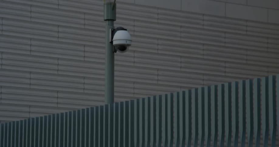 A security camera is attached to an outdoor light pole