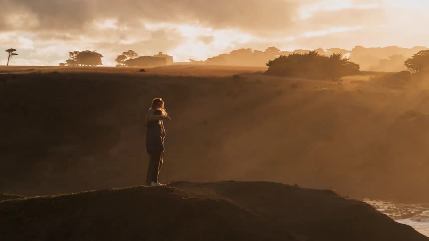 Two people walk together to see the sun set near the shore