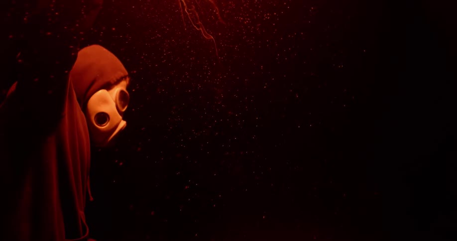 A person in a mask raises a burning flare to the sky at night