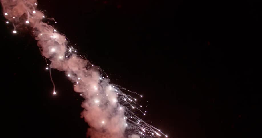 A man swings a lit flare outdoors