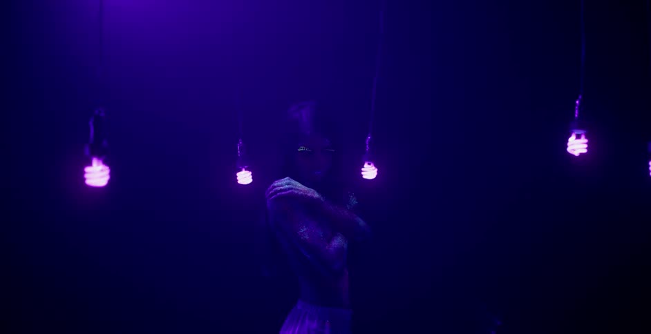 A woman in body paint is standing in a black lit room