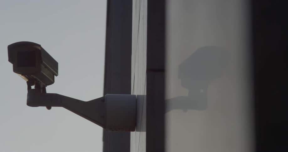 A camera sits mounted on the side of a building