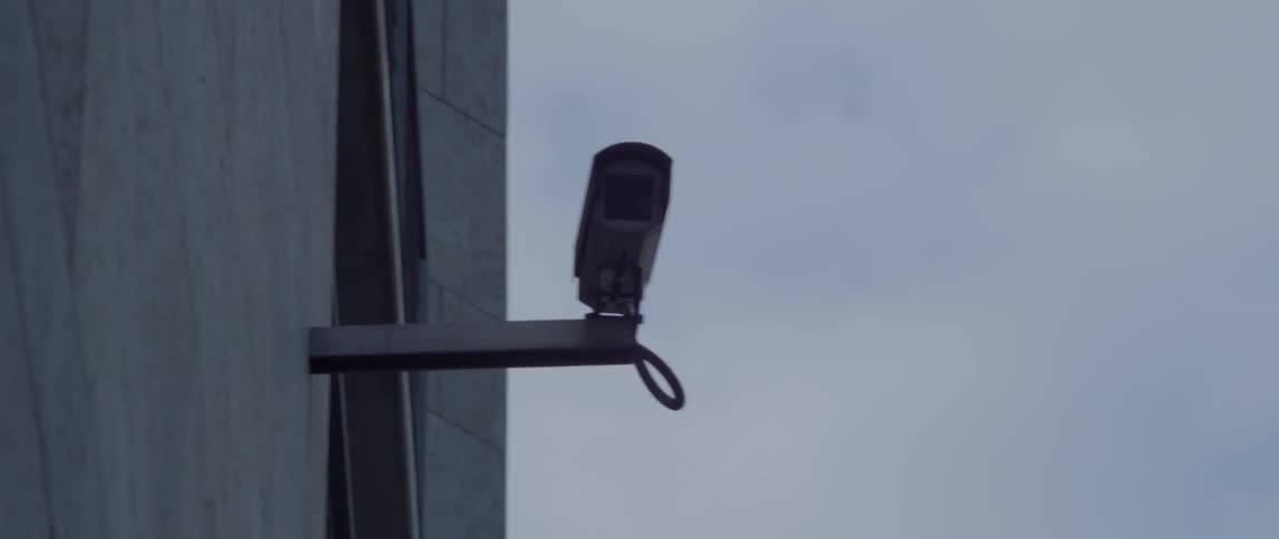 A security camera is attached to the side of a building